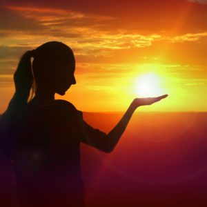 silhouette of girl holding the sun in her hand