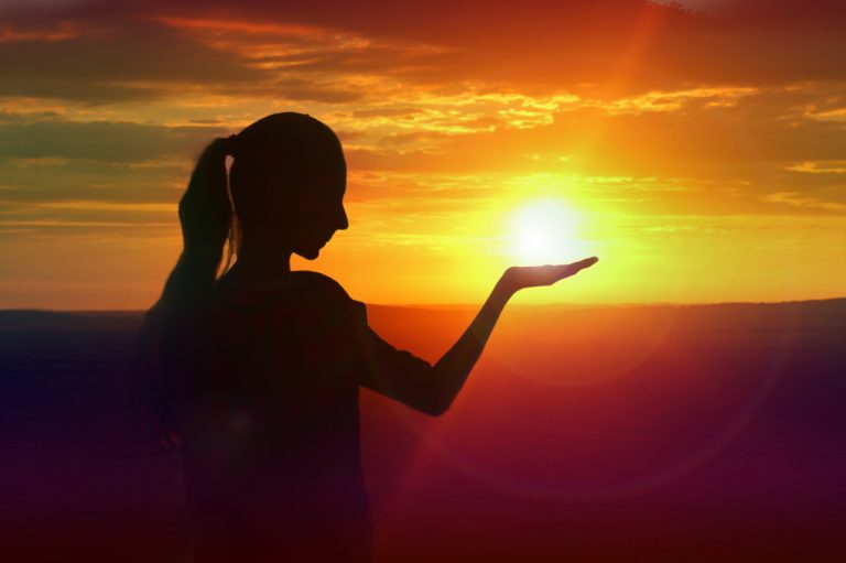 silhouette of girl holding the sun in her hand