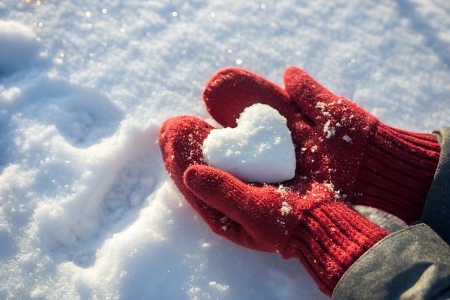 Winter Solstice red gloves holding a snow heart