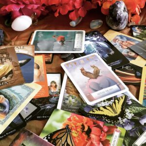 Many colorful oracle cards spread on a table with crystals a and flowers