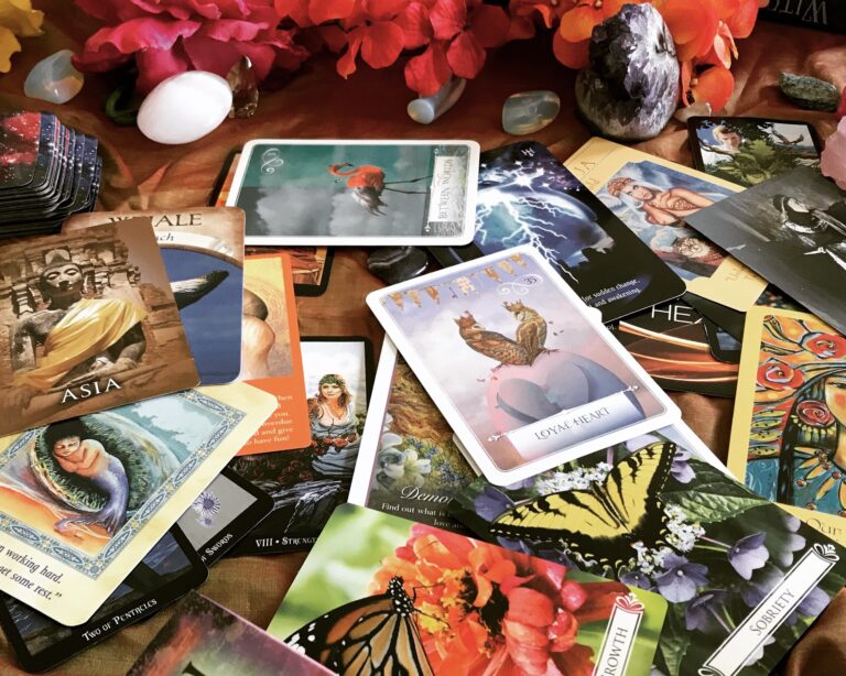 Many colorful oracle cards spread on a table with crystals a and flowers